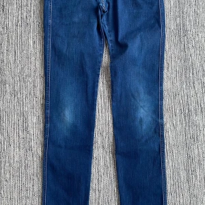 Blåa jeans i strl W30/L36 från Replay, modell Anbass slim fit - Blåa jeans i strl W30/L36 från Replay, modell Anbass slim fit.  Använda men i fint begagnat skick.  Mått Midjan: ca 41 cm Längd från grenen och ner: ca 92 cm  87% bomull, 9% polyester och 4% elastan  Kommer från ett djur och rökfritt hem.