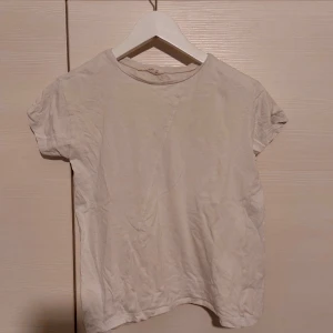 Vit t-shirt - En enkel och stilren vit t-shirt med korta ärmar. Perfekt basplagg för alla tillfällen.