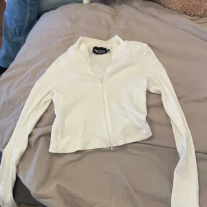Vit ribbad kofta från Pieces - Säljer en stilren vit ribbad kofta från Pieces. Den har en dragkedja framtill och långa ärmar. Perfekt för lager-på-lager-stil eller som ett lättare ytterplagg.