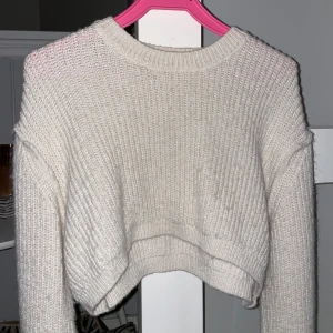 Vit stickad croppad tröja - Säljer en mysig vit stickad tröja med croppad passform. Tröjan har en rund halsringning, perfekt för kyliga dagar. Den är både stilren och bekväm. Storlek S. Köpt från chiquelle, fint skick. 