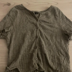 Grå ribbad topp från Shein - Säljer en grå ribbad topp från Shein med korta ärmar och knappar framtill.