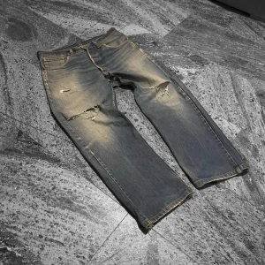 Levis Jeans med slitningar -  Säljer ett par blå distressed Levis med ganska större slitningar på knäna så notera att de inte är i bästa skicket, men fortfarande riktigt fräna, med spännande fade och en klassisk femficksdesign. W34, kontakta mig för mer bilder och eventuella mått. 