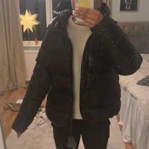 Colmar jacka - Snygg svart dunjacka från Colmar med dragkedja och huva. Perfekt för kyliga dagar med sin puffiga design och långa ärmar. Jackan har en stilren look och är lätt att matcha med olika outfits. Den är i italiensk storlek 44 men skulle säga att den sitter som s och kanske m. Helt ny och inte använd. Pris går att diskuteras!