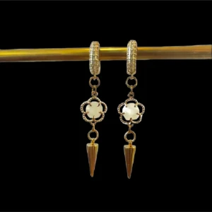 Guldörhängen med vita detaljer - Eleganta guldörhängen med vita blommor och spetsiga hängen. Perfekta för att ge en stilfull touch till din outfit. De har en glittrig yta som fångar ljuset vackert.