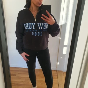 Svart sweatshirt  - Säljer en svart oversized sweatshirt med texten 'New York Eastside Track Team 1989' i blått och vitt från Gina tricot. Tröjan har en dragkedja och långa ärmar, perfekt för en avslappnad stil nu under vintern. Stl.Xxs Går även att användas som Xs, S & M