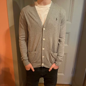 Grå Ralph Lauren cardigan  - Säljer en grå Ralph Lauren cardigan i storlek small som är i toppskick. Priset ligger på 699kr och nypris runt 2000kr. Kontakta mig vid intresse!
