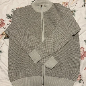 Grå stickad kofta från Park Lane - Säljer en stilren grå stickad kofta från Park Lane. Koftan har en dragkedja framtill och en ribbad krage samt muddar. Perfekt för kyliga dagar och ger en klassisk look.