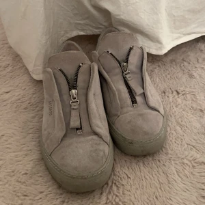 Grå Axel Arigato - Snygga grå Axel Arigato i mocka med dragkedja framtill. 