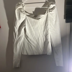 Vit långärmad topp från NA-KD - Säljer en stilren vit långärmad topp från NA-KD. Toppen har en elegant design med puffiga axlar.Perfekt för en chic look.
