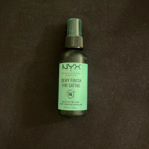 NYX Dewy Finish Setting Spray - NYX Professional Makeup Dewy Finish Setting Spray ger en fräsch och daggig look som håller i upp till 16 timmar. Perfekt för att fixera sminket och ge en långvarig finish. Flaskan innehåller 60 ml.