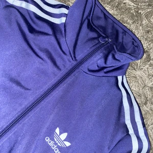 Lila adidas kofta - Riktigt fet adidas kofta med adidas tryck på ryggen. Den är i bra skick, kedjan funkar. 