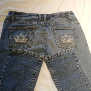Blå jeans med broderad krona - Säljer dessa straight jeans som påminnet om viktoria beckham jeans ,dem är lågmidjade jeans och jag är 155cm lång dem är lite långa på mig så oassar någon som är 160 och längre💕Märket är D.F.D JEANS.