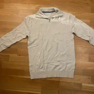 En beige half zip som är helt oanvänd. Har ett litet hål under kragen, kan sys ihop enkelt 