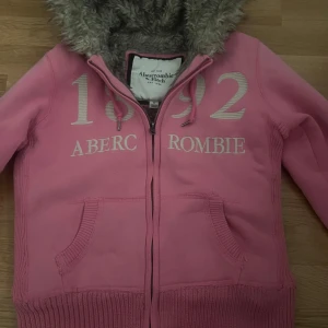Rosa hoodie från Abercrombie & Fitch - Säljer denna supermysiga rosa hoodie från Abercrombie & Fitch. Den håller väldigt varmt, perfekt till kyliga vinterdagar.