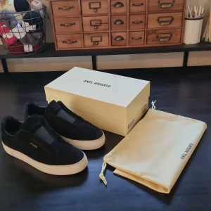 Arigato skor - Snygga svarta sneakers från Axel Arigato med vit sula. Skorna har en minimalistisk design med diskret logga på sidan. Perfekta för en stilren look. 9/10 i skick, använd fåtal gånger. Nypris 2650 kr. Mitt pris 1800.