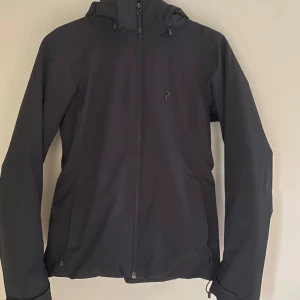 Skidjacka från PeakPerformance - SETPRIS TILLSAMMANS MED MATCHANDE BYXOR: 3000 ! Svart skidjacka från peakperformance, fint skick endast lite skavanker (bild på). Funkar jättebra i backen, när det blir för varmt finns det öppningar vid armhålorna, innerfickor finns samt glasögonputsare i fickan. Börjar bli för liten därför jag säljer. Önskas mer bilder skriv till mig! SKICKAR DIREKT