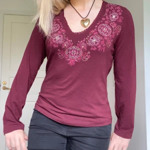 Vinröd långärmad tröja från Street One - Säljer en vinröd långärmad tröja från Street One med vackra broderade detaljer i rosa på bröstet. Det står stl 42 men den är liten i storleken, mer som en 38🥰