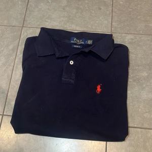 Navy blue Ralph pike - Tja, säljer denna snygga Ralph lauren piké. Den är otroligt bra skick, nästan så man tror den e ny, lite skrynklig för jag tvättade den bara. Perfekt för någon som S i storlek.                                              Skriv vid minsta fråga eller fundering!!!