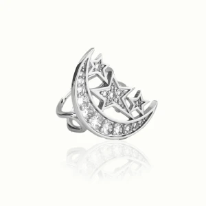 Silverfärgad ring med måne och stjärnor - Elegant ring i silverfärg med en design av en halvmåne och tre stjärnor. Ringen är dekorerad med gnistrande stenar som ger ett glittrigt utseende. Perfekt för att lägga till en touch av magi till din stil. Aldrig använd. Nypris 599. Säljer även matchande öronhängen.