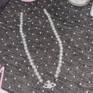 Pärlhalsband med silverdetalj - Elegant pärlhalsband med vita pärlor och en unik silverdetalj i mitten. Perfekt för att ge en klassisk touch till din outfit.