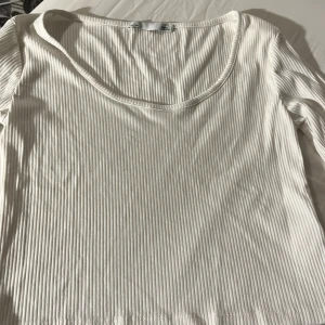 Vit ribbad topp - Säljer en stilren vit ribbad topp med rund halsringning. Perfekt för en enkel och snygg look. Toppen har långa ärmar och är gjord i ett mjukt material som känns skönt mot huden.