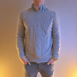 SOFT GOAT tröja i kashmir - Säljer en stilren grå tröja i mjukt kashmir-material. Tröjan har en klassisk passform med . Perfekt för en elegant och bekväm look. LITE LÖS VID KRAGEN