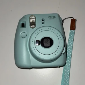 Instax mini 9, polaroidkamera - En nästintill oanvänd instax mini 9 polaroidkamera, som endast ligger och tar plats här hemma. Den är baby-blå har ett band med prickar och med på köpet får man även en kameraväska och ett klistermärke. Bilder till kameran får man dock köpa till samt 2st AA-baterier. Kameran kommer levereras i original boxen med följande instruktioner osv.🌸💞🫶🏼