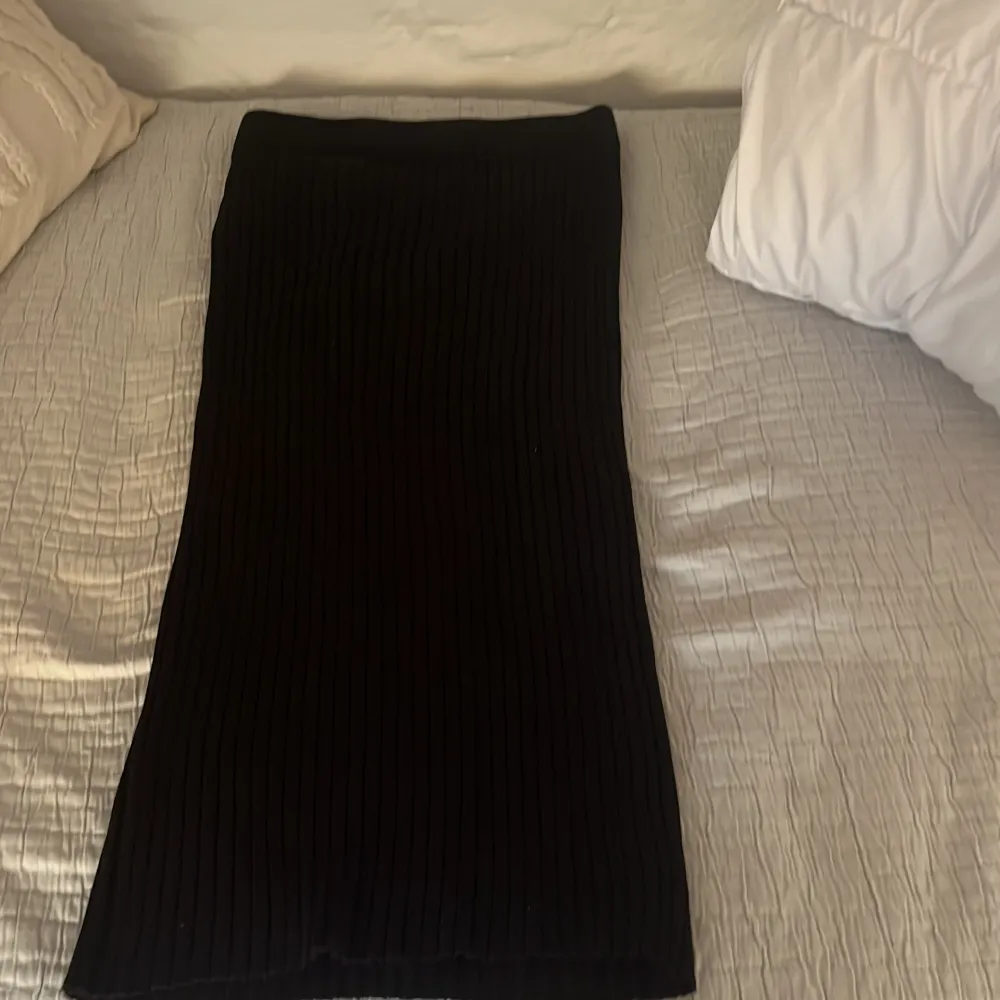 Snygg svart ribbad kjol från Lindex i storlek S. Kjolen har en stilren design med en elastisk midja för bekväm passform. Perfekt för att skapa en chic look.. Hameet.