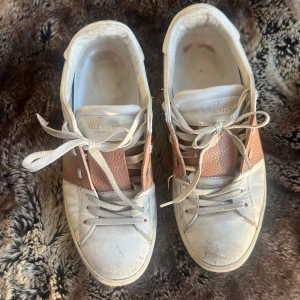 Valentino Garavani sneakers - Snygga Valentino Garavani sneakers i vitt och rosa med snörning och unika detaljer. De är använda väl så därav priset.