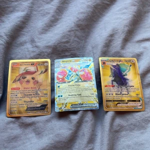 Pokémonkort med Ash Pikachu EX, Wugtrio EX och Gardevoir V - Tre Pokémonkort: Ash Pikachu EX med Static Body och Thunder, Wugtrio EX med Invicor Pump och Numbing Hold, samt Gardevoir V med Underworld Gate och Maxxi Prittroll. Korten har en glansig finish och är i olika färger med detaljerade illustrationer. Obs igen frakt 