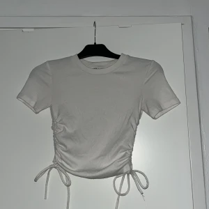 Vit ribbad topp från Zara - Vit ribbad topp från Zara med korta ärmar och knytning på båda sidor. 💞