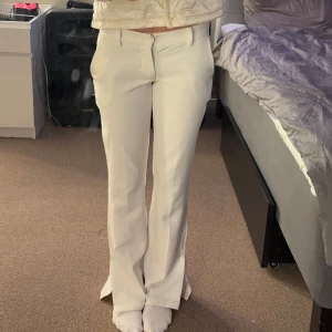 Vita kostymbyxor från BikBok - Snygga vita kostymbyxor från BikBok med en elegant bootcut-stil. Byxorna har en mid vayst midja och stängs med dragkedja och knapp framtill. Perfekta för en stilren look.