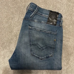 Blå jeans från Replay - Snygga blå jeans från Replay med en klassisk femficksdesign och diskreta slitningar. Passformen är anbass vilket motsvarar slim fit. Jeansen är i väldigt bra skick och är köpta för några veckor sedan. Använda max 10 gånger. Nypris ligger på 1899 och mitt pris är 699. Kan även sänka priset vid snabb affär. Hör av er vid frågor eller funderingar