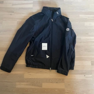 Moncler jacka  - Moncler vindjacka med luva. Passar L. Skicket är som ny inga defekter alls. Moncler extra knappar och en tag medföljer. Nypris över 10 000kr. 