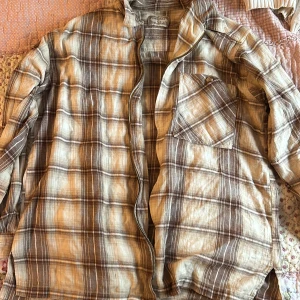 Brun och beige rutig skjorta från Natural Stuff - Säljer en brun och beige rutig skjorta från Natural Stuff. Skjortan har en dragkedja framtill och en bröstficka. Perfekt för en avslappnad stil. Jag har använt den som oversized och den superskön och bekväm👍🏻