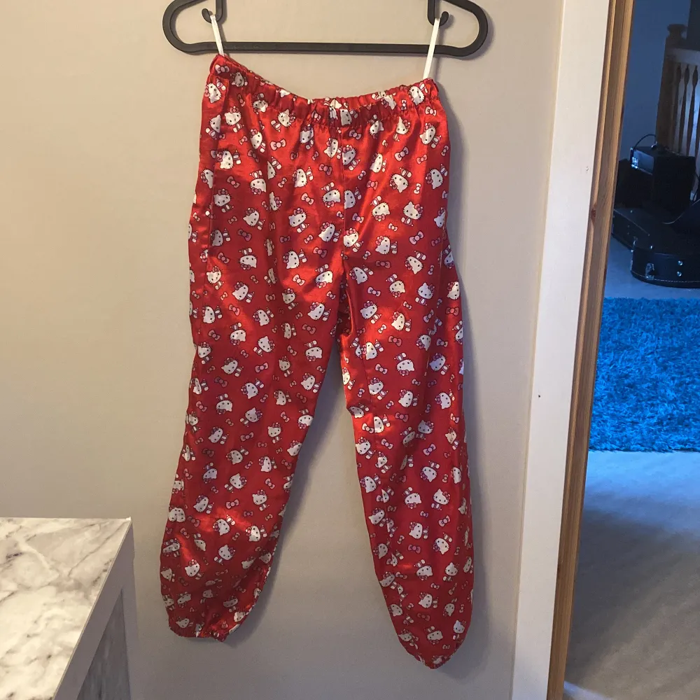 Säljer en superfin röd Hello Kitty pyjamas i satin. Skjortan har långa ärmar och knappar framtill. Byxorna har en bekväm resår i midjan. Perfekt för mysiga kvällar hemma! 💤. Muu.