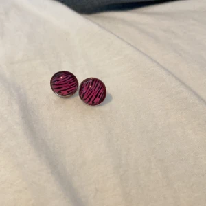 Mcbling örhängen  - Snygga rosa örhängen med zebramönster. Perfekta för att ge en färgklick till din outfit. De har en rund form och är lätta att bära.