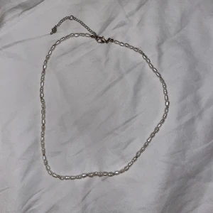 Två pärlhalsband - Säljer två pärlhalsband för 50kr. Det första har oregelbundna pärlor med justerbar kedja och det andra har jämna, runda pärlor med ett klassiskt lås. 