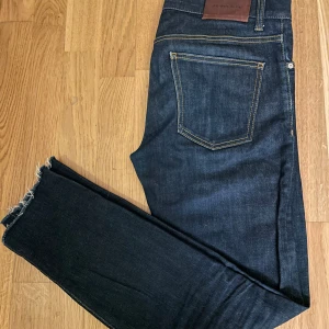 Mörkblå jeans från J.Lindeberg - Snygga mörkblå jeans från J.Lindeberg med slim fit/skinny Klassisk femficksmodell med dragkedja och knapp. Perfekta för en grish look.