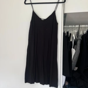Svart klänning med smala axelband - Snygg svart klänning med smala axelband och v-ringning. Perfekt för en stilren look. Klänningen har en enkel och elegant design som passar till många tillfällen. Jättefin 