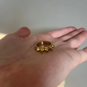 Guldfärgad ring med nitar Edblad  - Snygg guldfärgad ring med nitar som ger en edgy look. Perfekt för att addera lite attityd till din outfit. Ringen har en slät insida för bekväm passform.