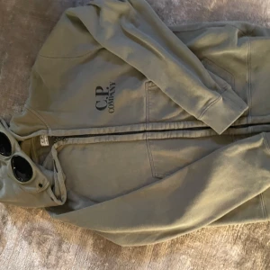 Grön CP Company hoddie 14 år - Grön CP Company hoddie med zip. 14 år. Använd men fint skick.