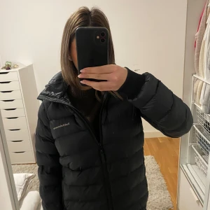 Svart dunjacka från Peak Performance - Säljer en svart dunjacka från Peak Performance i bra skick men den är använd. Jackan är perfekt för vintern med sin varma vaddering och har en praktisk huva. Den har en dragkedja framtill och långa ärmar. Supermysig och stilren för kalla dagar! Det är inte mycket defekter på den förutom att en liten lapp på högra fickan är borta men inget man lägger märket till🩷🩷