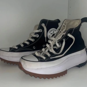 Svarta Converse med platåsula - Säljer ett par svarta Converse med vit platåsula och bruna detaljer. Skorna har klassisk snörning och är i bra skick. Perfekta för både vardag och fest! 🖤