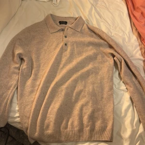 Beige kashmirtröja från Massimo Dutti - Säljer en supermjuk och stilren beige kashmirtröja från Massimo Dutti. Perfekt för både höst och vinter med sin klassiska pikédesign och långa ärmar. Tröjan har en krage med knappar och är i mycket bra skick. Passar perfekt för en elegant och bekväm look.