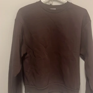Brun sweatshirt från Gina Tricot - Säljer en enkel och stilren brun sweatshirt från Gina Tricot. Perfekt för en avslappnad look. Tröjan har långa ärmar och en rund halsringning. Passar bra till både jeans och mjukisbyxor. Perfekt för höst och vinter!