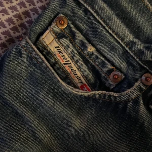 Mörkblå jeans från Diesel - Säljer ett par mörkblå jeans från vintage Diesel i bra skick. De har tyvärr en slitning vid skrevet som är ihop sytt men det syns inte när man har på sig dom. Detta är mina favvo byxor men säljer för att dom är för korta för mig. Har en liten slitning/hål längst ner på byxbenet.