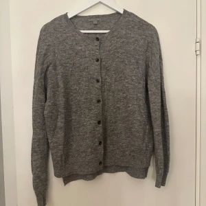 Grå kofta med knappar - Mysig grå kofta i mycket bra skick. Perfekt för höst och vinter med sina långa ärmar och klassiska knappar framtill. Den är gjord av ett mjukt material som känns skönt mot huden. Passar både till vardags och lite finare tillfällen.