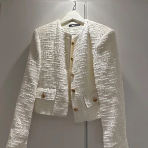 Vit kavaj från Gina Tricot - Säljer en stilren vit kavaj från Gina Tricot i storlek 36. Den har en elegant struktur med guldknappar framtill och på fickorna. Perfekt för både vardag och fest! 🕊️
