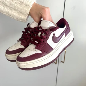 Nike sneakers i vinrött och vitt - Säljer ett par snygga Nike sneakers i vinrött och vitt. De har en klassisk design med snörning och en bekväm sula. Perfekta för både vardag och träning. Skorna är i mycket bra skick!